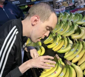 Adult with disability practicing Life Skills Training by choosing bananas independently at a grocery market.