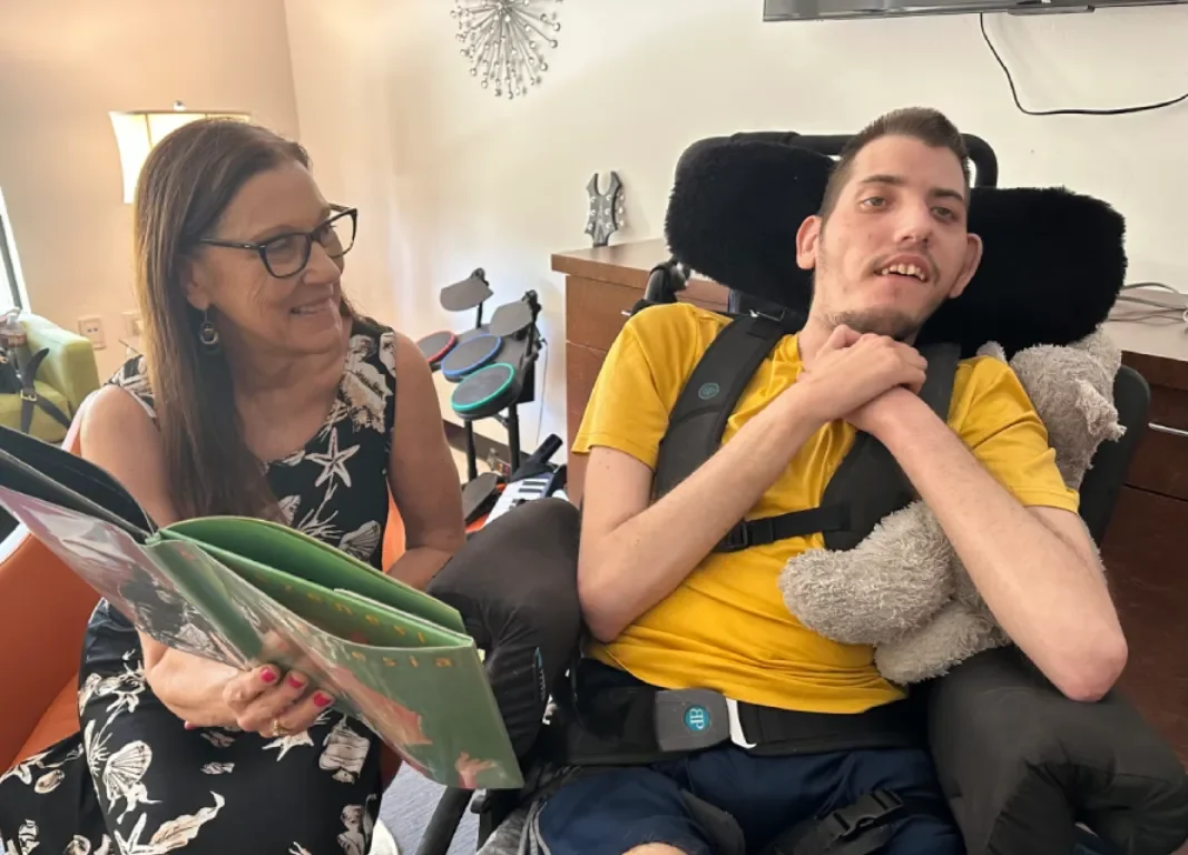 A staff member reading to a participant during a school to adult day programs activity at Cortney's Place.