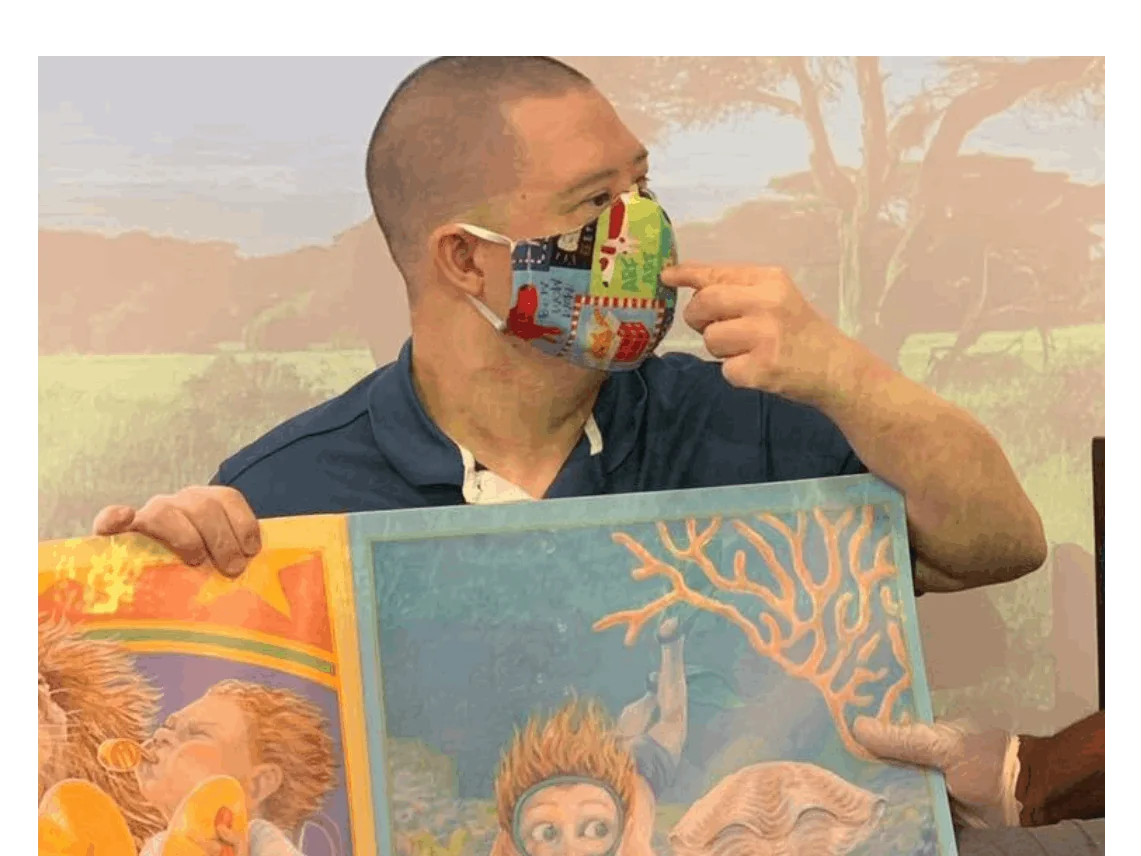 Adult with IDD holding a picture book during a creative program activity