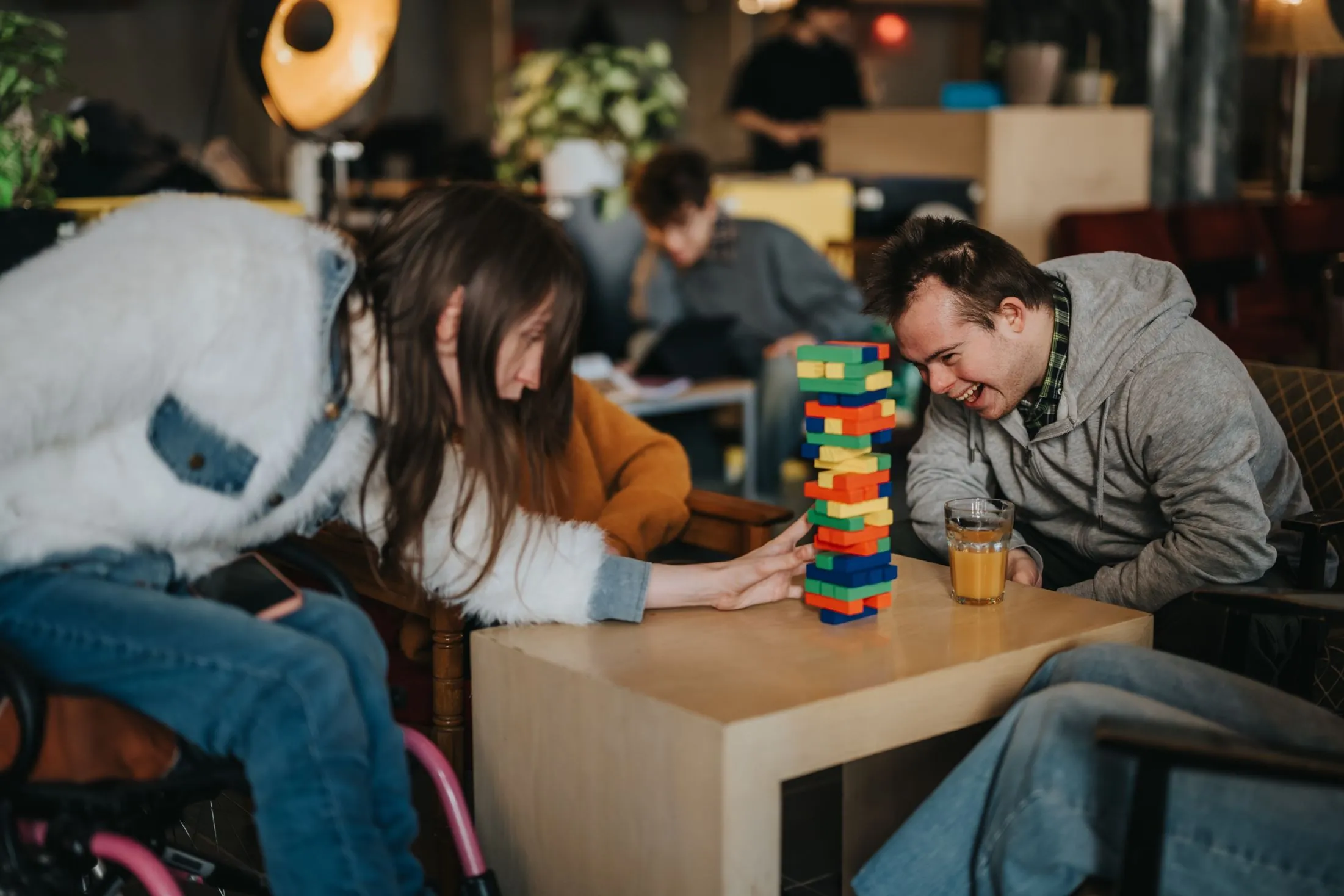 Adults with IDD playing a block stacking game together at a local café during a community participation outing