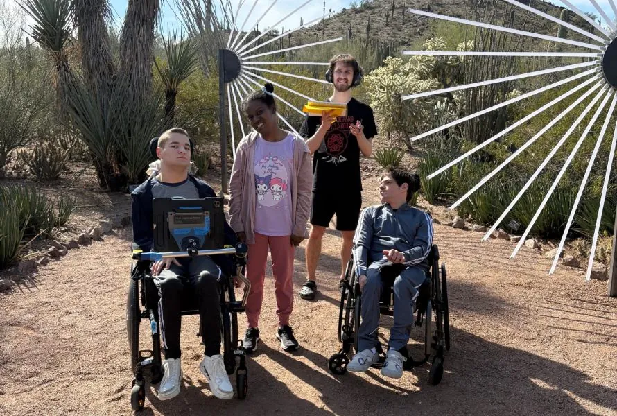 Adults with IDD enjoying a summer community outing at a desert garden with accessible wheelchairs and support staff